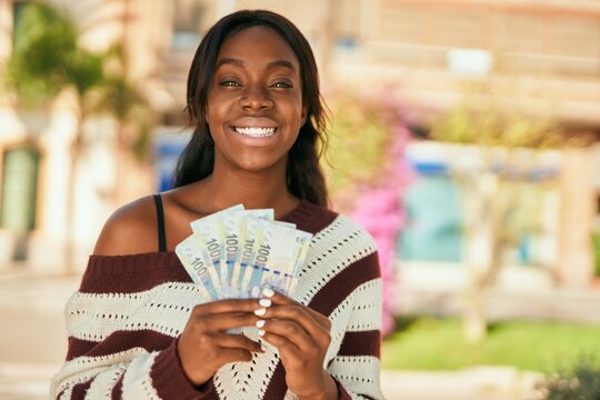 Young african american woman smiling happy holding south africa rands at the park.