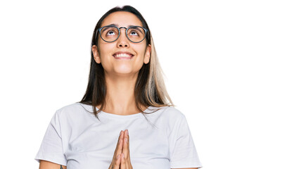 Young hispanic woman wearing casual white t shirt begging and praying with hands together with hope expression on face very emotional and worried. begging.