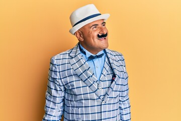 Mature middle east man with mustache wearing vintage and elegant fashion style looking away to side with smile on face, natural expression. laughing confident.