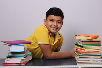 indian school boy or scholar kid with stack of books