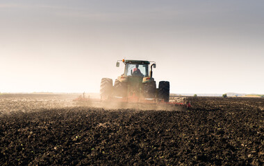 Fototapeta premium Tractor is preparing the land at dusk