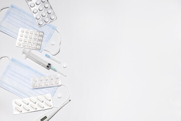 medicines on a white isolated background. medical mask, pills and syringe