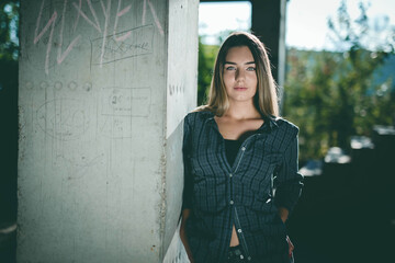 Young Caucasian woman with green eyes leaning on the wall with graffitis