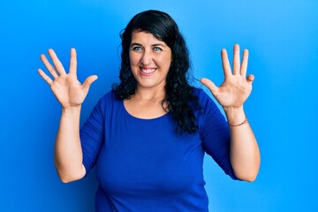 Plus size brunette woman wearing casual blue shirt showing and pointing up with fingers number nine...