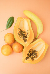 Fototapeta na wymiar papaya fruit, oranges and banana on orange background