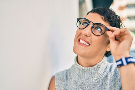 Young plus size woman smiling happy leaning on the wall at the city.