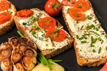 Healthy food rye bread with cream cheese and tomato. Sliced tomatoes with bread. Baked garlic with cheese and ham.