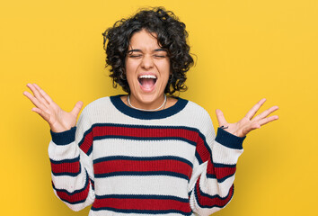 Young hispanic woman with curly hair wearing casual clothes celebrating mad and crazy for success...