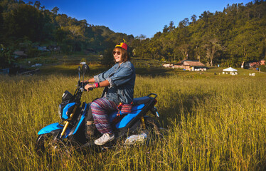 Asian woman tourist on motorcycle at the meadow.