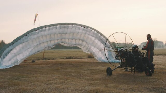 Pitot trying to inflate parachute before start. Pre-flight check procedure. Tandem motor powered paragliding at twilight. 