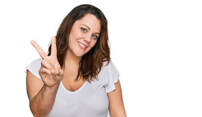 Young plus size woman wearing casual white t shirt showing and pointing up with fingers number two while smiling confident and happy.