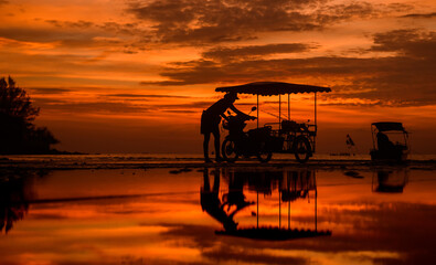 Silhouette of transport motorcycle on the beach with the man.