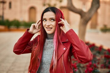 Fototapeta premium Young caucasian girl smiling happy listening to music using headphones at the city.