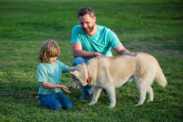 Obraz premium Smiling Father and Son with Pet. Happy Family with Loyal Pedigree Dog have Fun at the Backyard.