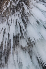 The rock on the frozen lake Baikal is covered with a thick layer of blue ice: many icicles and...