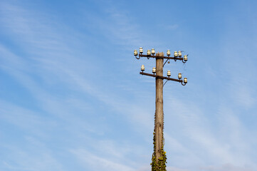 low angle view of old and decaying telegraphy pole at a train station in Germany against blue sky