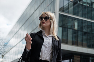 Portrait of a young business woman in the City of London wearing sunglasses.