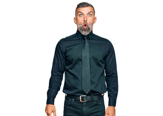 Fototapeta premium Middle age handsome man wearing business clothes scared and amazed with open mouth for surprise, disbelief face