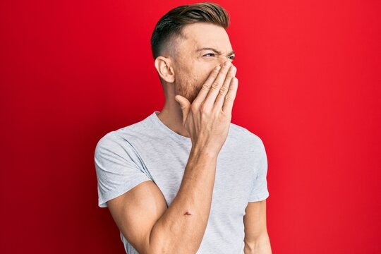 Young redhead man wearing casual grey t shirt shouting and screaming loud to side with hand on mouth. communication concept.