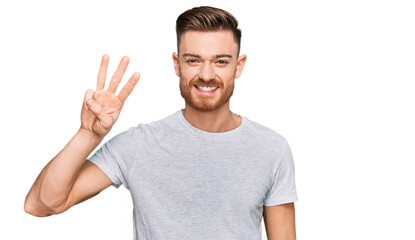 Naklejka premium Young redhead man wearing casual grey t shirt showing and pointing up with fingers number three while smiling confident and happy.