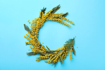 Obraz premium Beautiful floral composition with mimosa flowers on light blue background, flat lay. Space for text