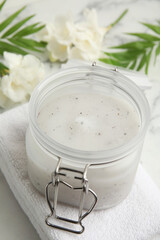 Jar of salt scrub and towel on white table