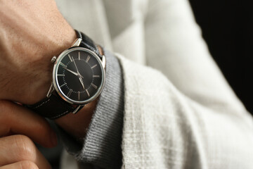 Businessman in jacket with luxury wrist watch on black background, closeup - obrazy, fototapety, plakaty
