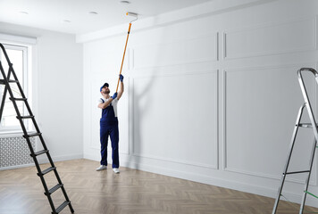 Handyman painting ceiling with white dye indoors, space for text