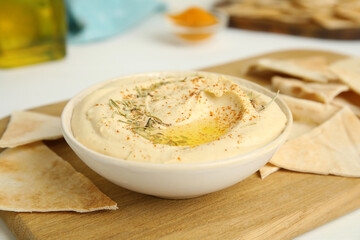 Delicious hummus served with pita chips on wooden board