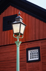 Old 19th century lamp post in front of a Scandinavian traditional red, black and white painted building