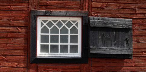 Old window with handmade glas panes on a 200 years old traditional red and black painted Scandinavian cottage