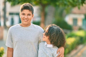 Adorable latin brother and sister hugging at the park.