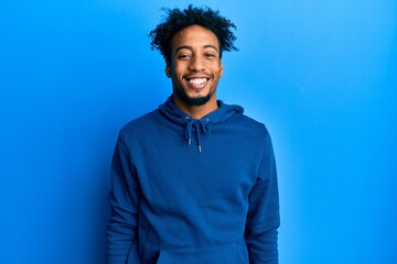Young african american man with beard wearing casual sweatshirt with a happy and cool smile on...