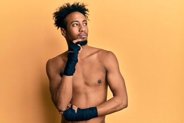 Fototapeta premium Young african american man with beard using boxing protection thinking concentrated about doubt with finger on chin and looking up wondering