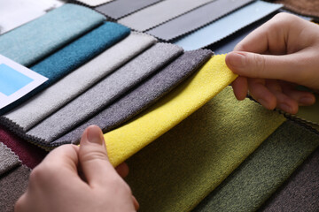 Woman choosing among colorful fabric samples, closeup