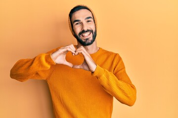 Obraz premium Young hispanic man wearing casual clothes smiling in love doing heart symbol shape with hands. romantic concept.