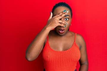 Young african american woman wearing casual style with sleeveless shirt peeking in shock covering...