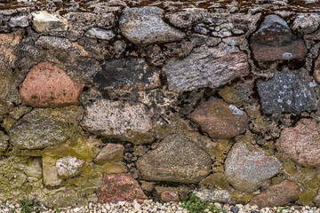 A wall of colored stones with moss.