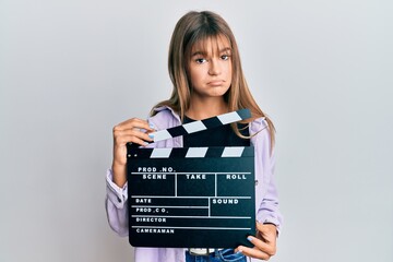 Teenager caucasian girl holding video film clapboard depressed and worry for distress, crying angry...