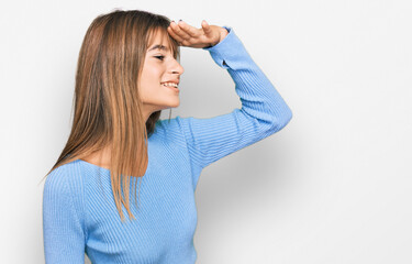 Fototapeta premium Teenager caucasian girl wearing casual clothes very happy and smiling looking far away with hand over head. searching concept.