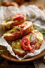 Obraz na płótnie Canvas Bruschetta with cheese, salami and tomato sprinkled with rosemary, close-up view