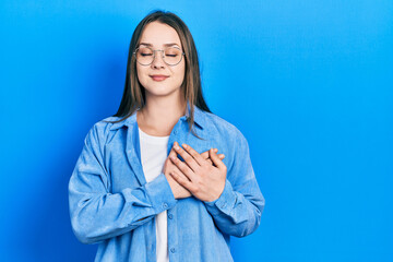 Young hispanic girl wearing casual clothes and glasses smiling with hands on chest with closed eyes and grateful gesture on face. health concept.