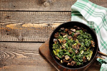 fried champignons with spinach in a pan.
top view. Copy space.