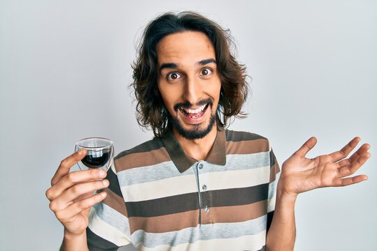 Young hispanic man drinking a cup of coffee celebrating achievement with happy smile and winner expression with raised hand