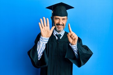 Middle age hispanic man wearing graduation cap and ceremony robe showing and pointing up with fingers number six while smiling confident and happy.