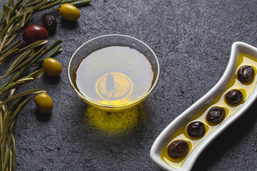 Olive oil and olives image on black insulated table. Generally, olive oil is used in salads, stuffed peppers and cooking.