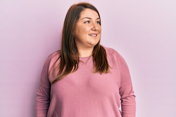 Fototapeta premium Beautiful brunette plus size woman wearing casual winter sweater looking to side, relax profile pose with natural face and confident smile.