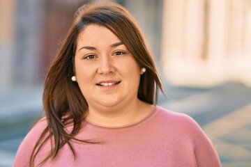 Young hispanic plus size woman smiling happy standing at the city.