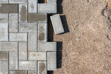 Laying gray concrete paving slabs in a house walkway. Process of construction of brick paved...