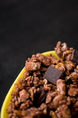 Cereals of chocolate with little chocolates in a yellow pot on a black table 